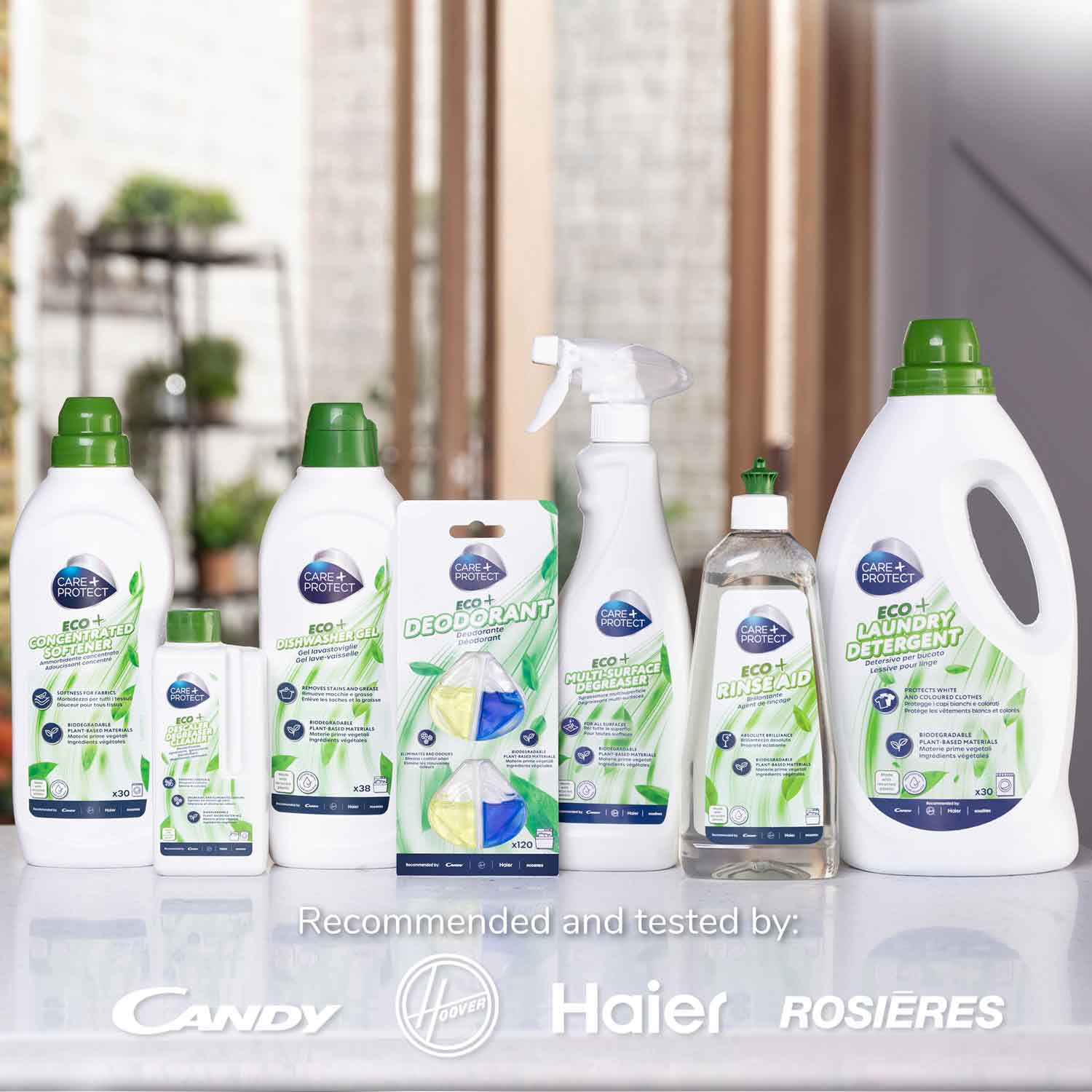 Cleaning products with green accents are displayed on a counter. Bottles include laundry detergent, dish soap, and deodorant. Background shows a kitchen. Text: "Recommended and tested by: Candy, Hoover, Haier, Rosières."