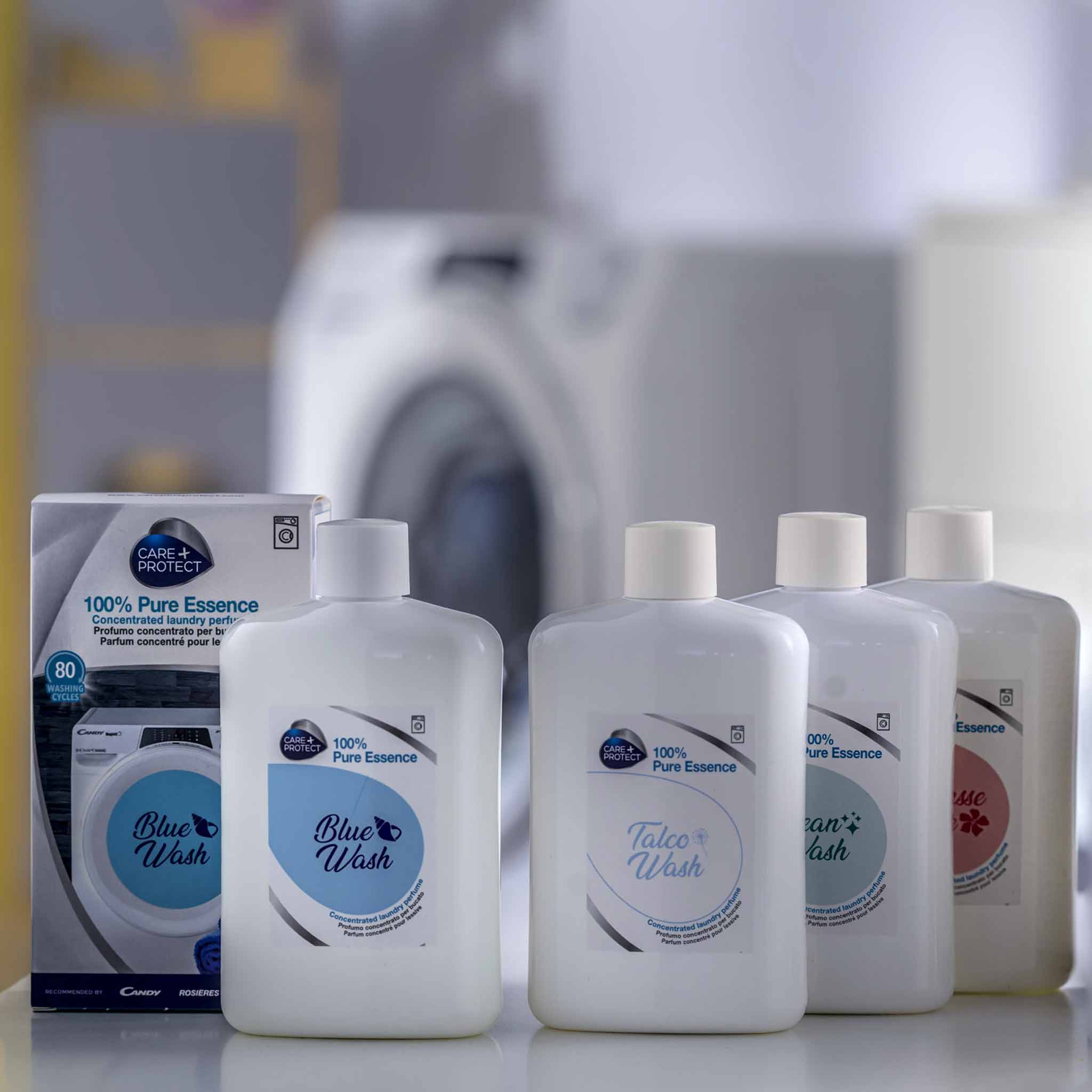 Bottles of liquid detergent labeled "Blue Wash" stand in front of a washing machine. The text on boxes reads, "100% Pure Essence." The environment is a modern laundry room.